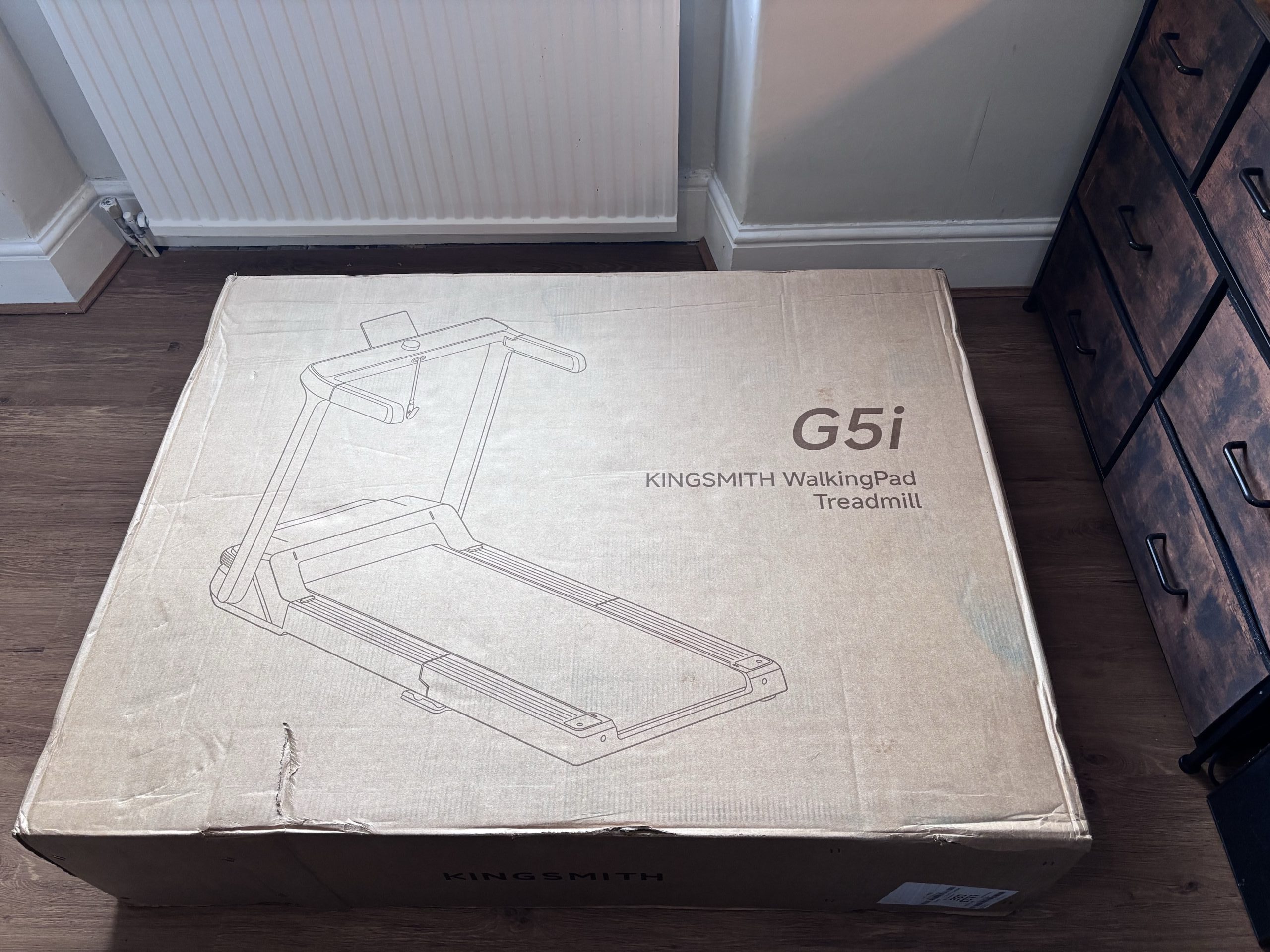WalkingPad G5i box laid flat on the floor, unopened with straps removed